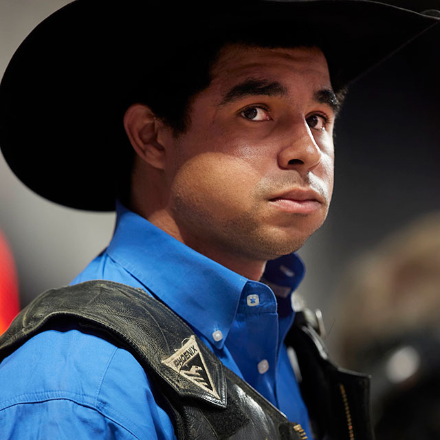 Laramie Mosely, wearing a blue shirt and a cowboy hat, looking away from the camera.